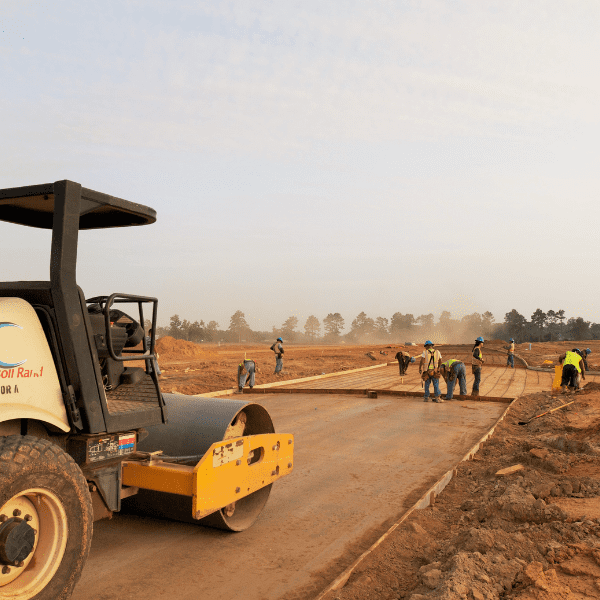 Road roller compacting pavement during roadway construction on a Texas development project